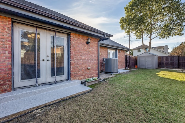 rear view of house featuring french doors, central AC unit, a yard, and a storage shed