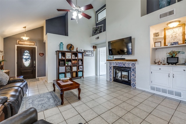 living room featuring built in features, light tile patterned floors, high vaulted ceiling, a tiled fireplace, and ceiling fan