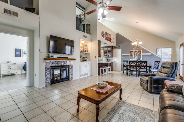 tiled living room featuring ceiling fan with notable chandelier, a tiled fireplace, and high vaulted ceiling