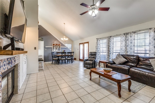 tiled living room featuring high vaulted ceiling, a tiled fireplace, and ceiling fan with notable chandelier