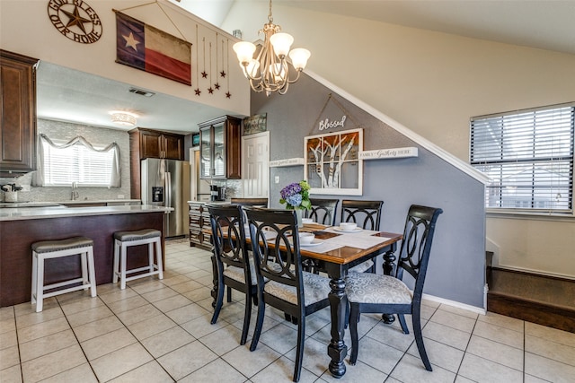 dining room featuring an inviting chandelier, vaulted ceiling, and light tile patterned floors