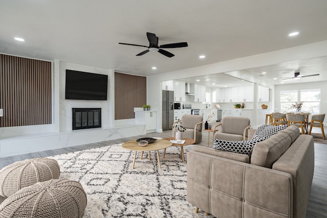 living room with sink, a fireplace, ceiling fan, and light hardwood / wood-style flooring