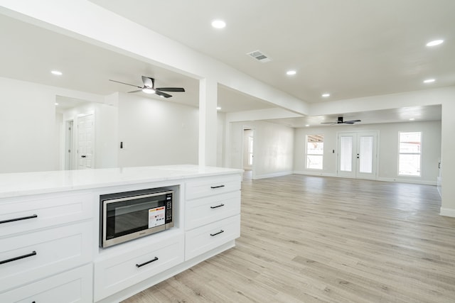 kitchen with white cabinets, ceiling fan, and light hardwood / wood-style flooring