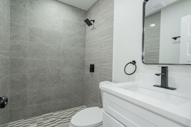 bathroom with tiled shower, vanity, and toilet