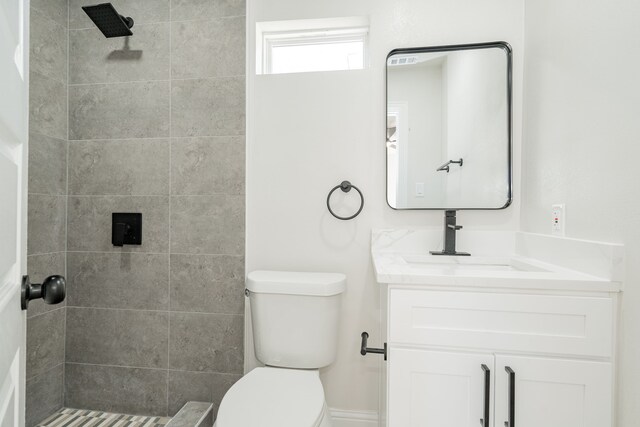 bathroom featuring toilet, vanity, and tiled shower