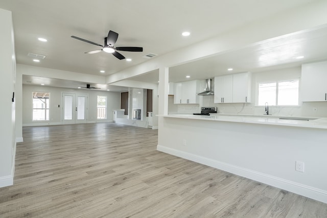 kitchen featuring white cabinets, electric range, plenty of natural light, and wall chimney exhaust hood