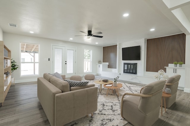 living room featuring plenty of natural light, ceiling fan, wood-type flooring, and a premium fireplace