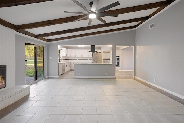 unfurnished living room with light tile patterned floors, a brick fireplace, vaulted ceiling with beams, and a sink