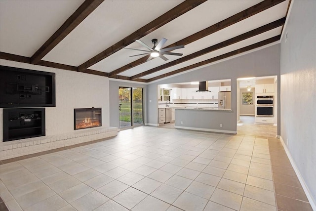 unfurnished living room featuring a ceiling fan, baseboards, lofted ceiling with beams, light tile patterned flooring, and a glass covered fireplace