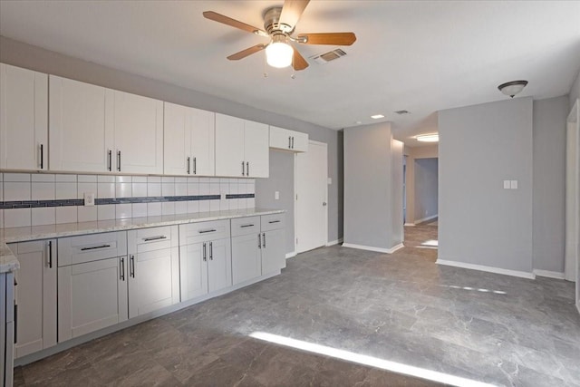 kitchen with tasteful backsplash, visible vents, baseboards, light stone countertops, and a ceiling fan