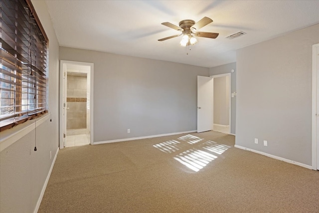 unfurnished bedroom with ceiling fan, ensuite bathroom, and light colored carpet