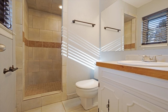 bathroom with toilet, vanity, tile patterned floors, and a tile shower