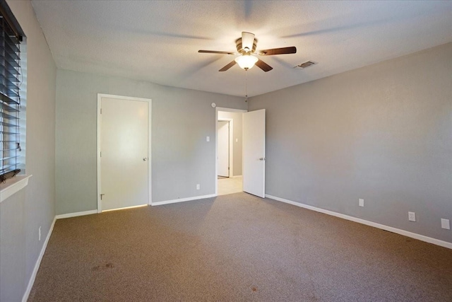 unfurnished room with visible vents, ceiling fan, carpet flooring, and baseboards