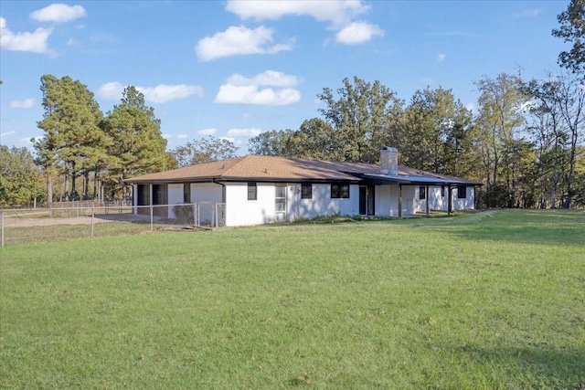 rear view of property with a lawn, a chimney, and fence