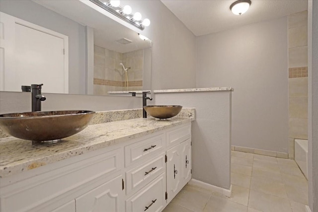 full bath featuring tile patterned flooring, double vanity, baseboards, and a sink