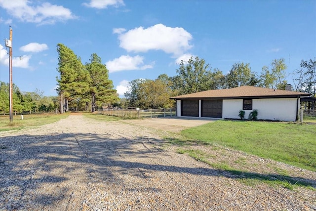 exterior space featuring a lawn, an attached garage, concrete driveway, and fence