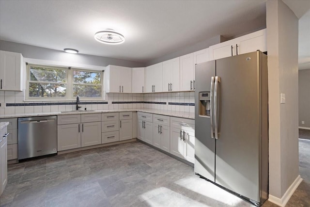 kitchen featuring tasteful backsplash, baseboards, light stone countertops, stainless steel appliances, and a sink