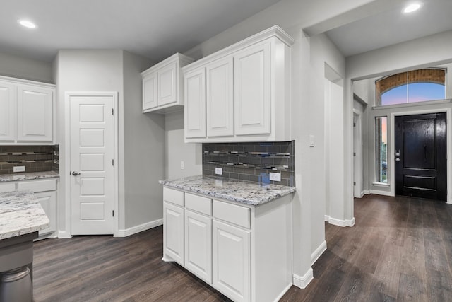 kitchen featuring white cabinets, light stone countertops, dark wood-type flooring, and decorative backsplash