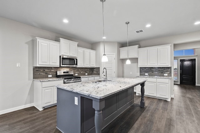 kitchen featuring stainless steel appliances, dark hardwood / wood-style flooring, white cabinets, sink, and a kitchen island with sink