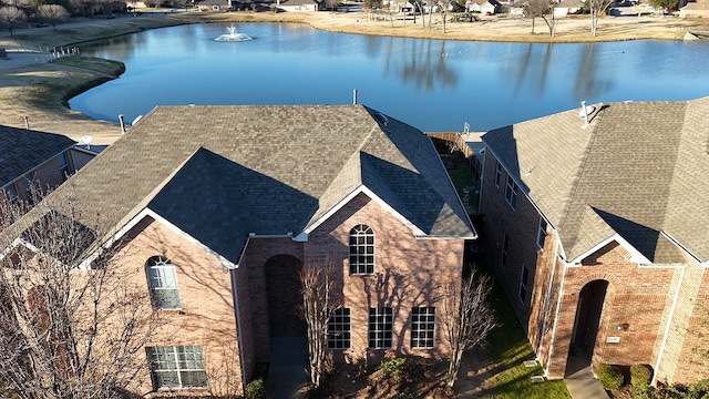 view of front of home featuring a water view, a shingled roof, and brick siding