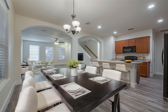 dining area featuring arched walkways, ceiling fan with notable chandelier, visible vents, and recessed lighting