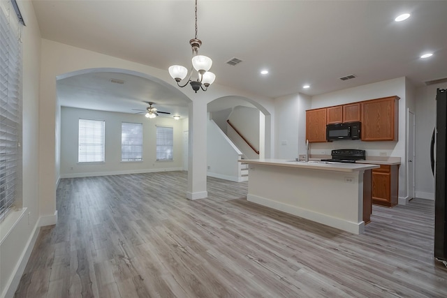 kitchen with arched walkways, visible vents, open floor plan, black appliances, and brown cabinetry