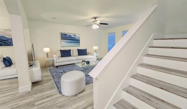 living room featuring stairs, wood finished floors, and a ceiling fan