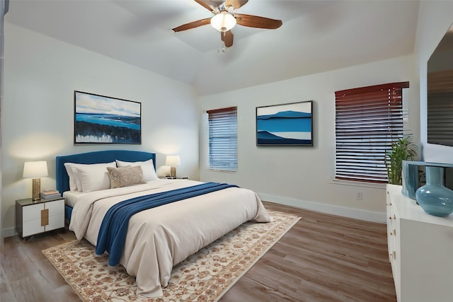 bedroom with ceiling fan, hardwood / wood-style flooring, and vaulted ceiling