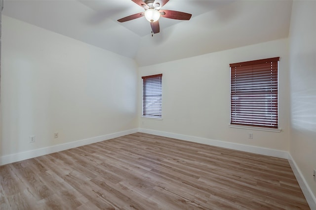 empty room with lofted ceiling, ceiling fan, wood finished floors, and baseboards