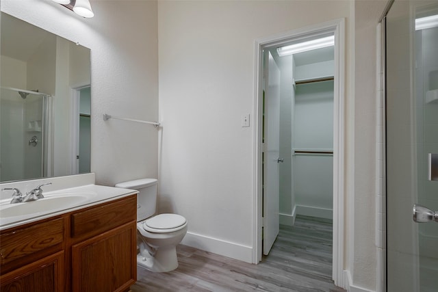 bathroom featuring hardwood / wood-style floors, toilet, a shower with door, and vanity