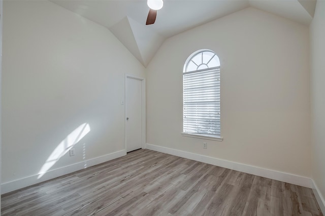 spare room featuring lofted ceiling, light wood-type flooring, baseboards, and ceiling fan