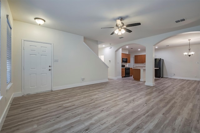 unfurnished living room featuring light wood-style floors, visible vents, baseboards, and ceiling fan with notable chandelier