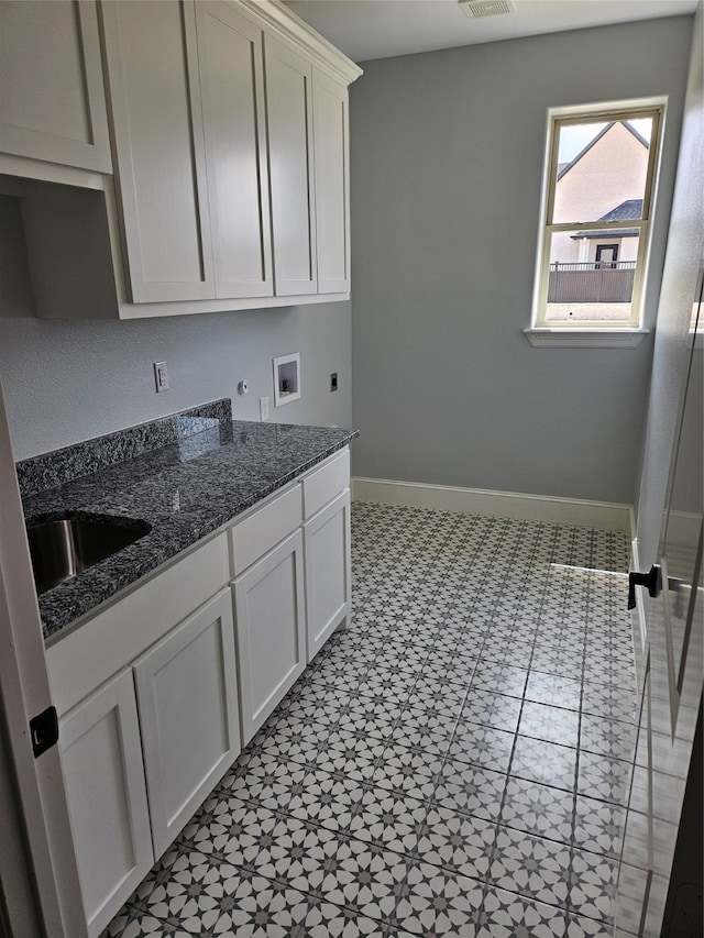 laundry area with light tile patterned flooring, hookup for an electric dryer, washer hookup, cabinets, and sink