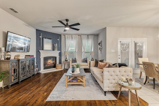 living room with hardwood / wood-style floors, ceiling fan, and a textured ceiling