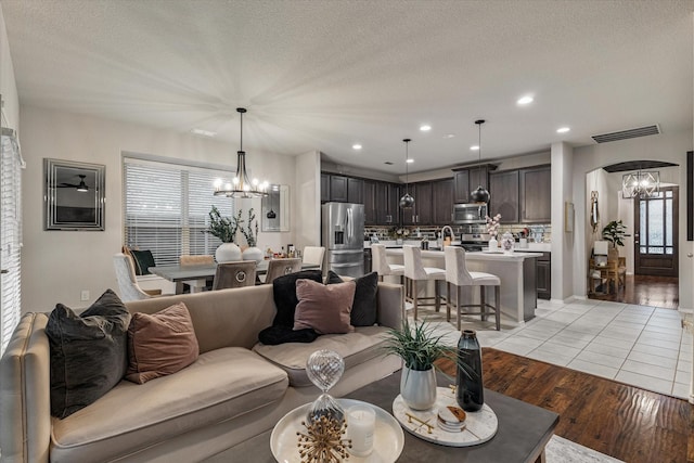 living room featuring a chandelier, light hardwood / wood-style floors, and a textured ceiling