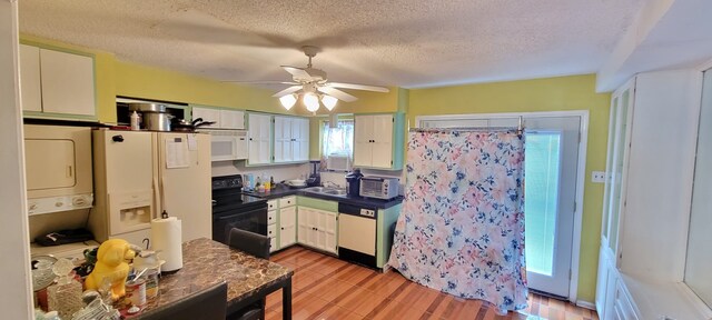 kitchen with white appliances, ceiling fan, stacked washing maching and dryer, a textured ceiling, and white cabinetry