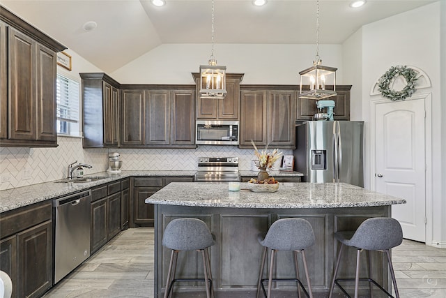 kitchen with stainless steel appliances, vaulted ceiling, a kitchen island, and tasteful backsplash