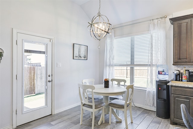 dining area featuring an inviting chandelier, vaulted ceiling, light hardwood / wood-style floors, and plenty of natural light