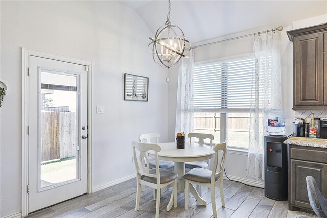 dining room featuring lofted ceiling, a notable chandelier, light wood finished floors, and baseboards