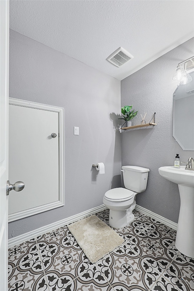 bathroom with toilet, sink, and a textured ceiling