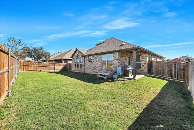 back of property featuring a fenced backyard, a yard, brick siding, and roof with shingles