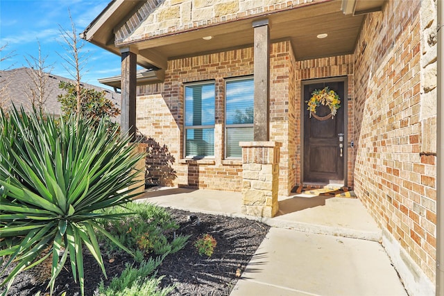 view of front of home featuring a garage, brick siding, driveway, stone siding, and roof with shingles