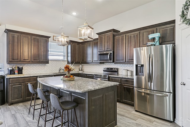 kitchen with tasteful backsplash, stainless steel appliances, a kitchen island, hanging light fixtures, and a breakfast bar area