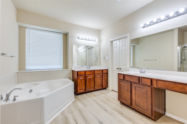 bathroom with hardwood / wood-style floors, vanity, and shower with separate bathtub