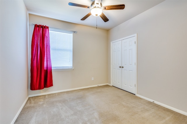 unfurnished bedroom with a closet, light colored carpet, and ceiling fan