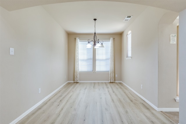 unfurnished dining area with light wood-type flooring and a notable chandelier