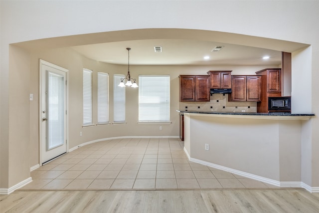 kitchen with light hardwood / wood-style floors, a chandelier, decorative light fixtures, and kitchen peninsula