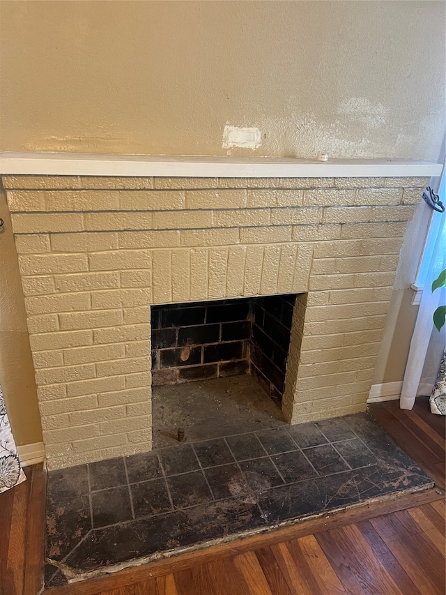 interior details with wood-type flooring and a brick fireplace