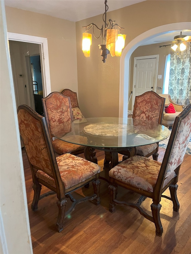 dining room with hardwood / wood-style flooring and ceiling fan with notable chandelier