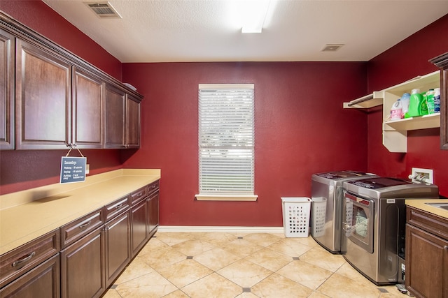 laundry room featuring washer and dryer, cabinets, and a textured ceiling